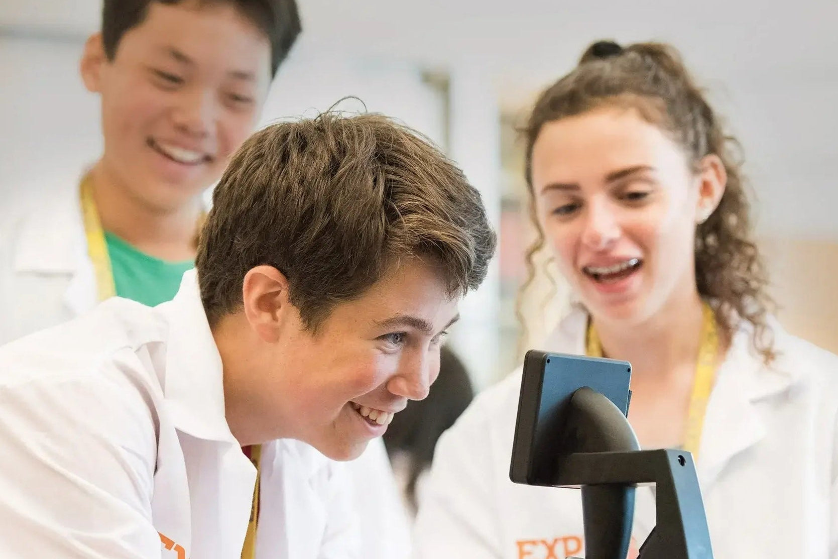 Middle school students engaged in a summer program science workshop, exploring with a microscope at EXPLO.