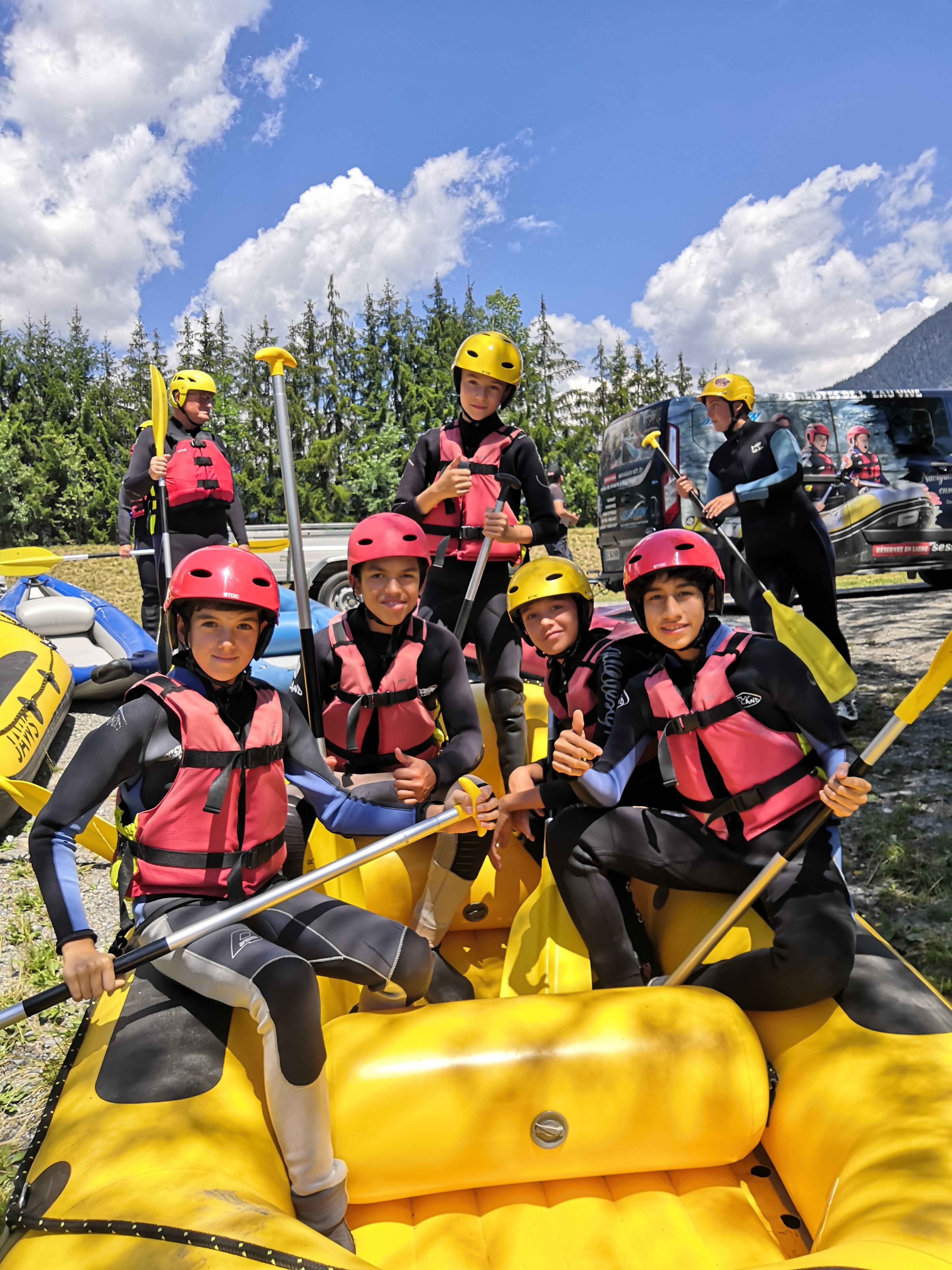 Teens in pink life vests enjoying rafting at a summer camp in the French Alps, ready for adventure and new friendships.
