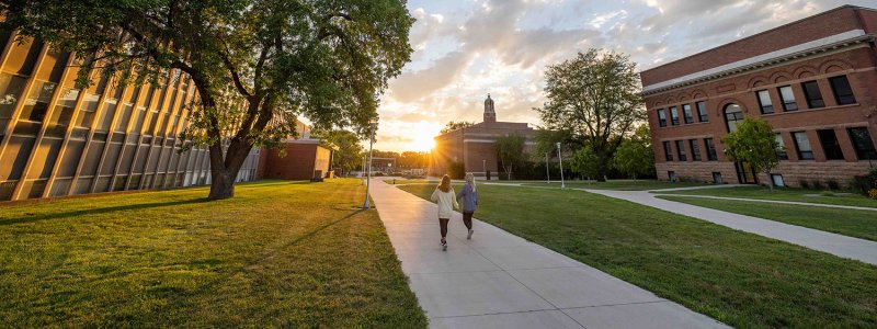 Students walking on campus during sunset, highlighting summer programs for high school and college.