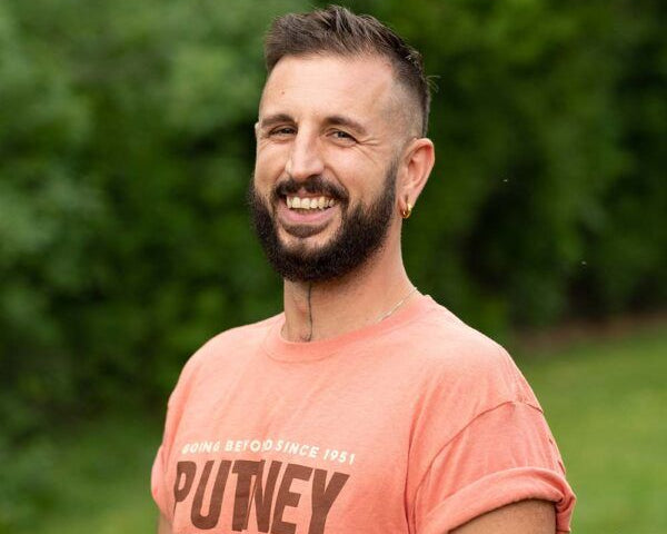 Smiling male program leader wearing Putney shirt, promoting summer programs and educational travel experiences.