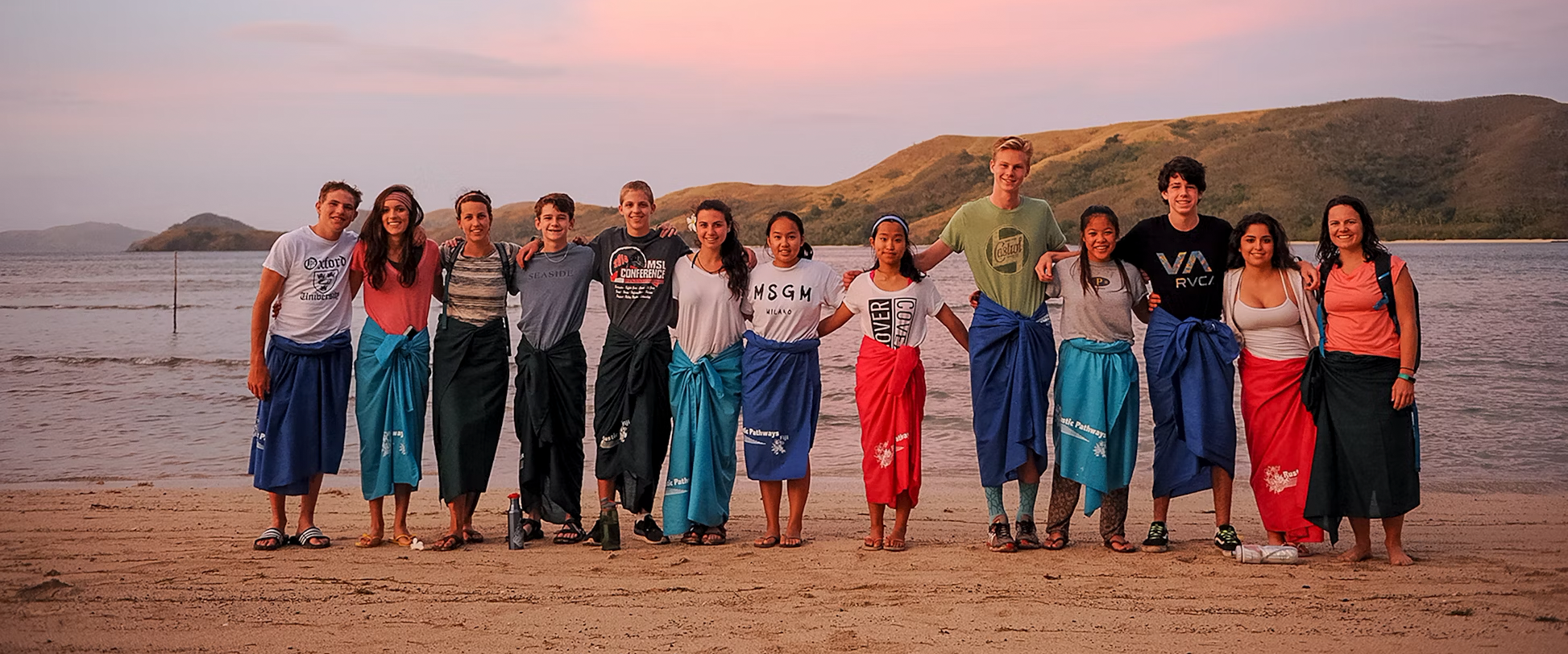 Group of diverse high school students at a summer camp by the beach, dressed in casual clothing, enjoying the scenic sunset.