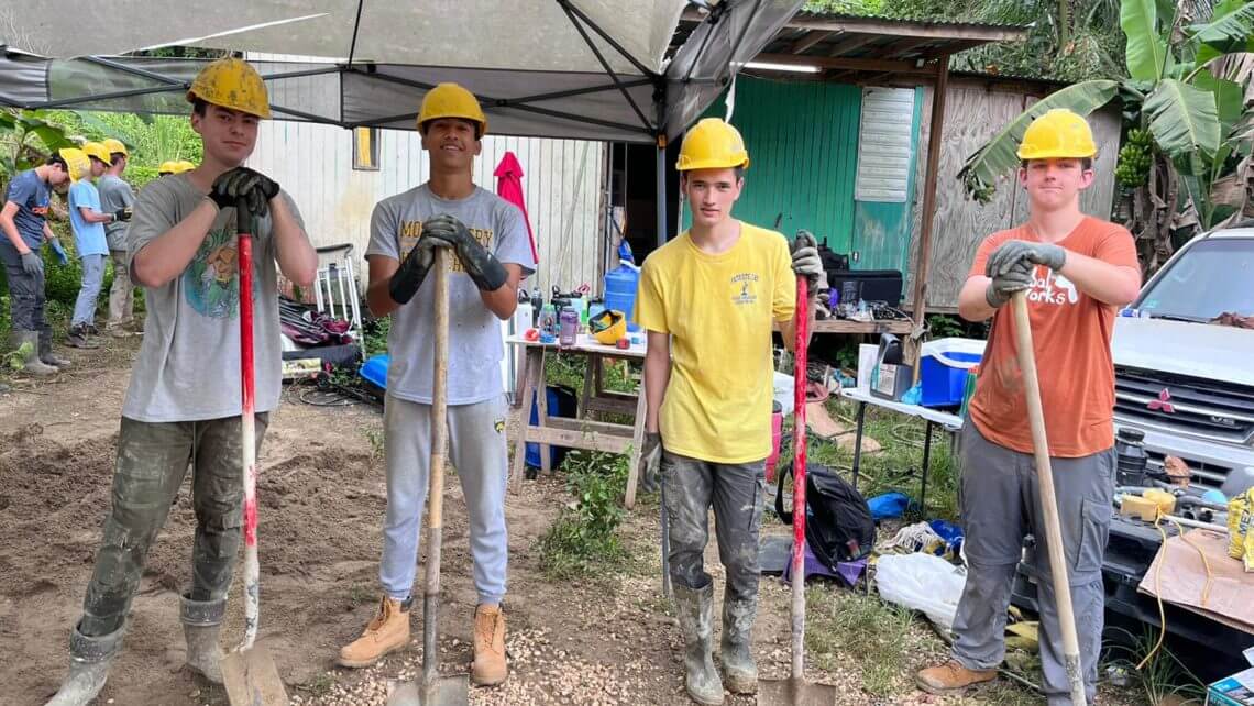 Teens in hard hats holding shovels during a hurricane relief service trip in Puerto Rico, part of a summer program for high school students.
