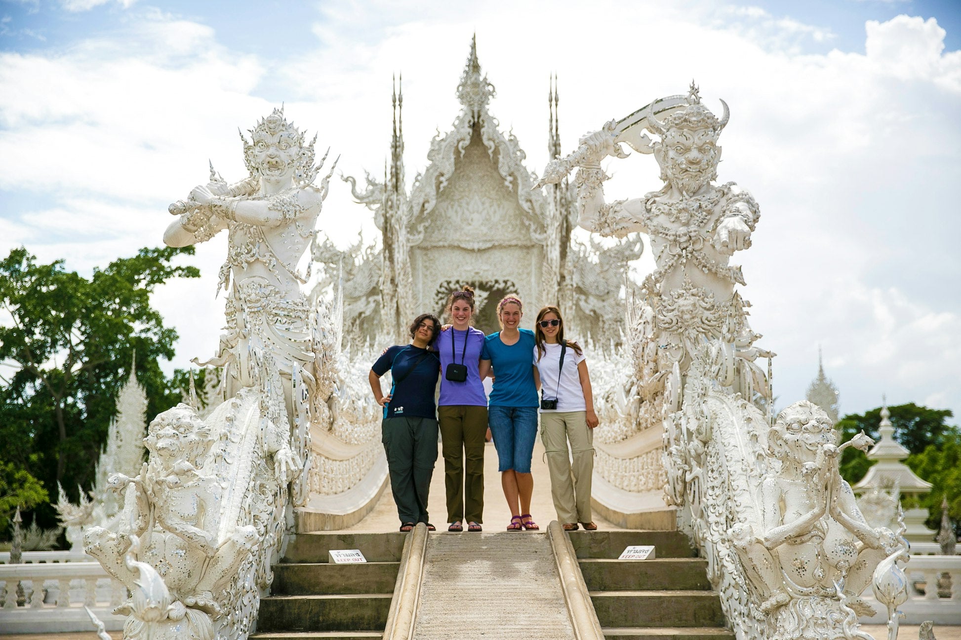 Four teenagers posing at the stunning White Temple in Thailand during their summer expedition.