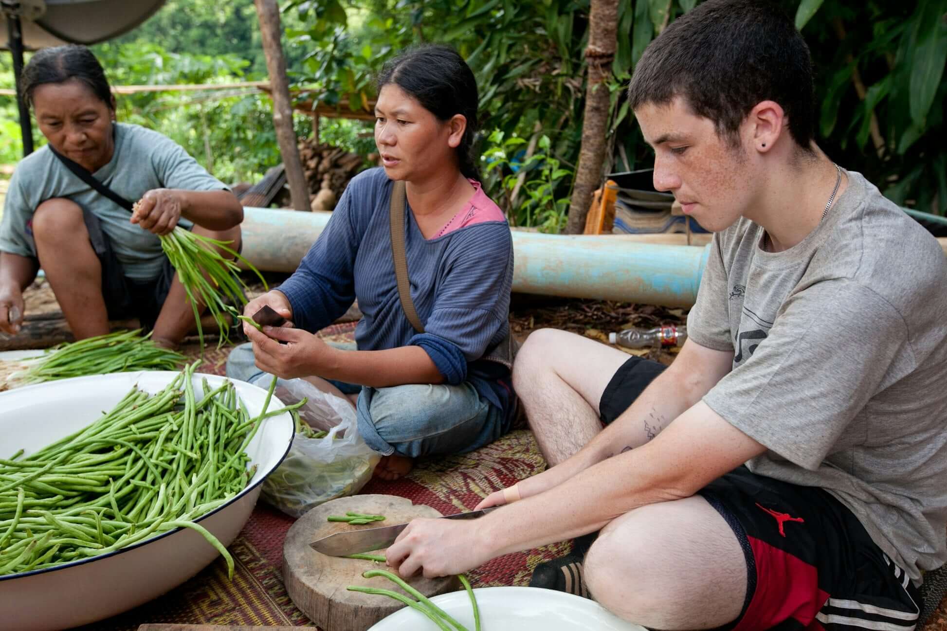 Teen participating in a cultural exchange, preparing green beans with local villagers in Northern Thailand.