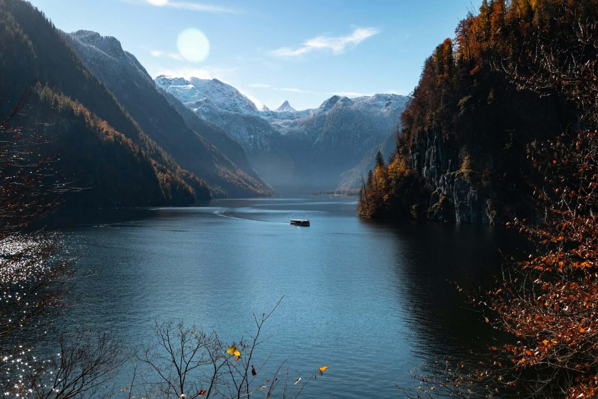 Serene alpine lake with mountains in the background and a boat cruising through the tranquil water.