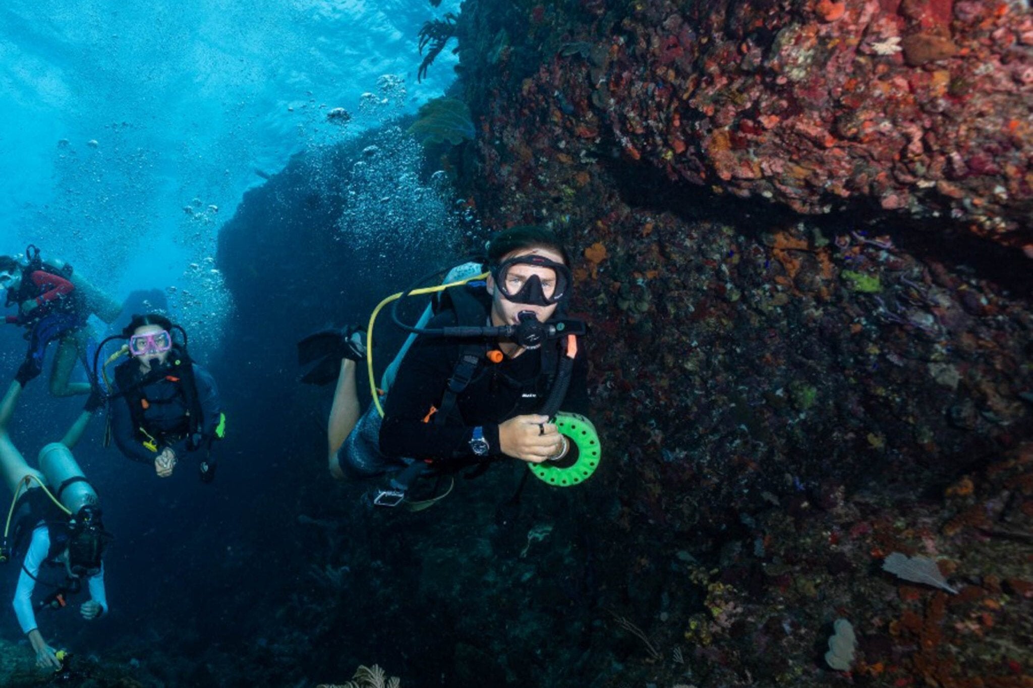 Teens scuba diving underwater exploring marine life during summer programs in the Caribbean.