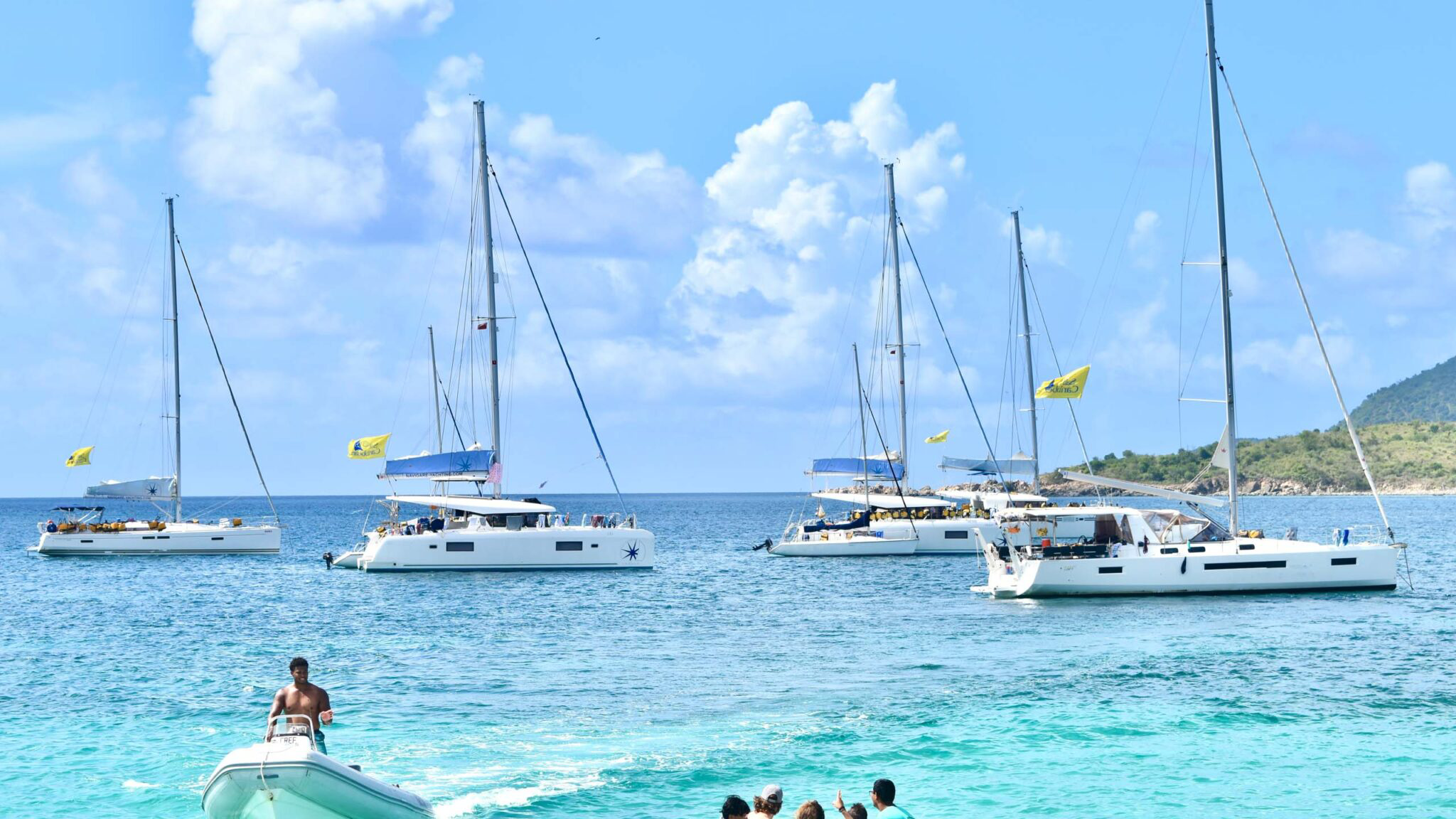 Scenic view of sailboats anchored in a clear blue sea under a bright sky, perfect for summer adventures and relaxation.