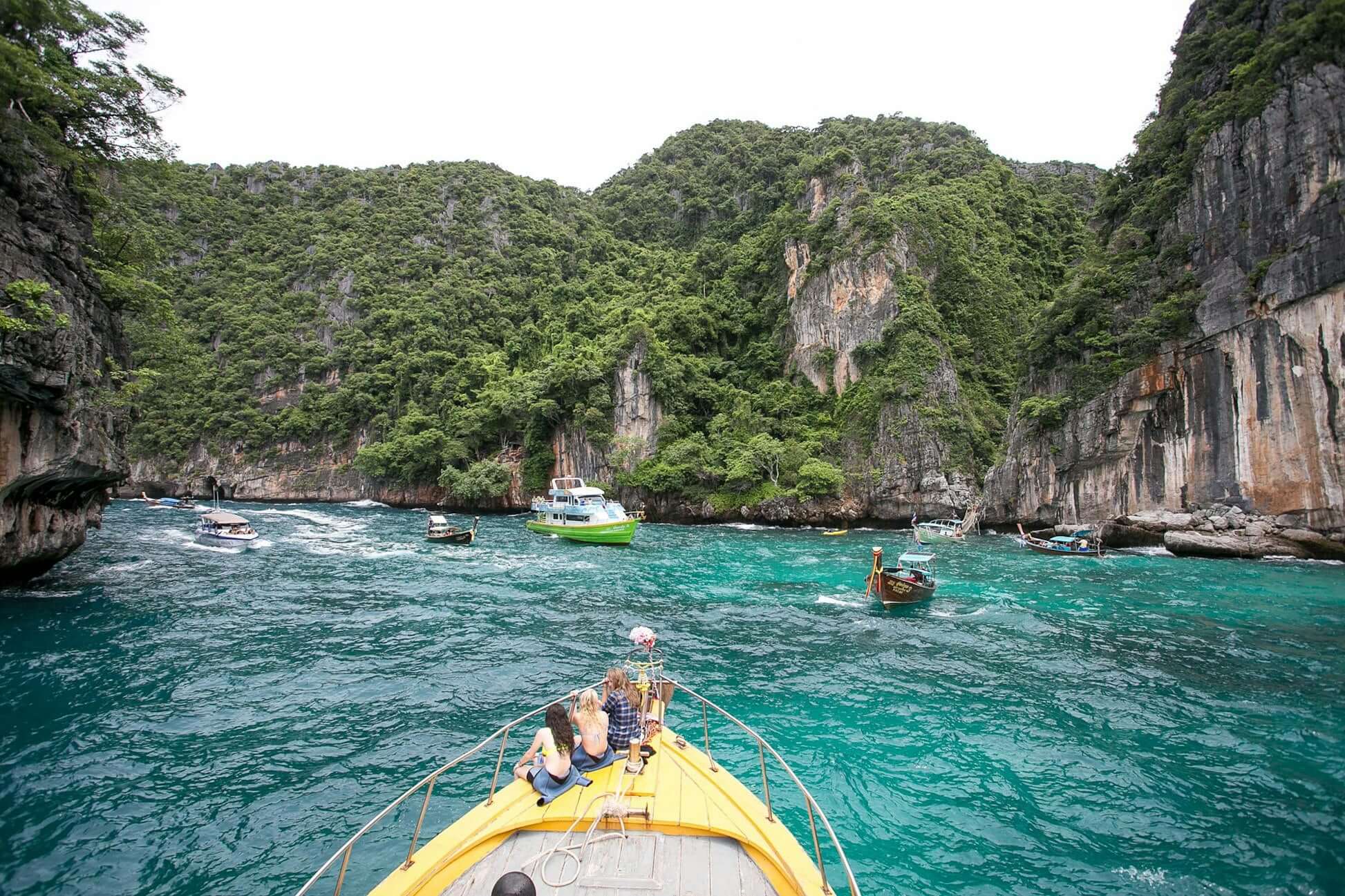 Adventurous high school students exploring stunning limestone cliffs in northern Thailand by boat.