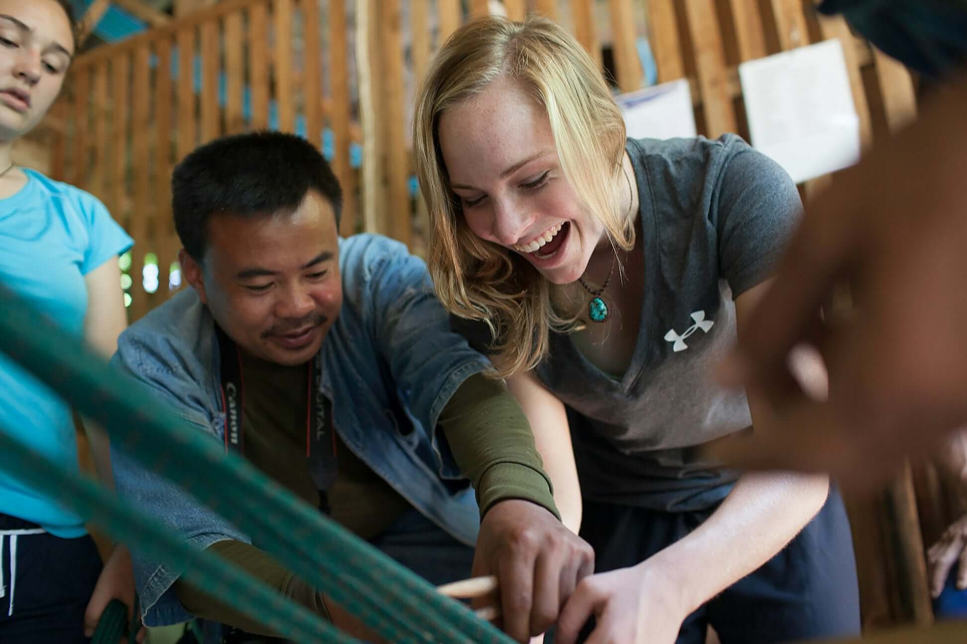 Junior mahout training with laughter and teamwork in a Thai elephant conservation project, perfect for teen travel adventures.