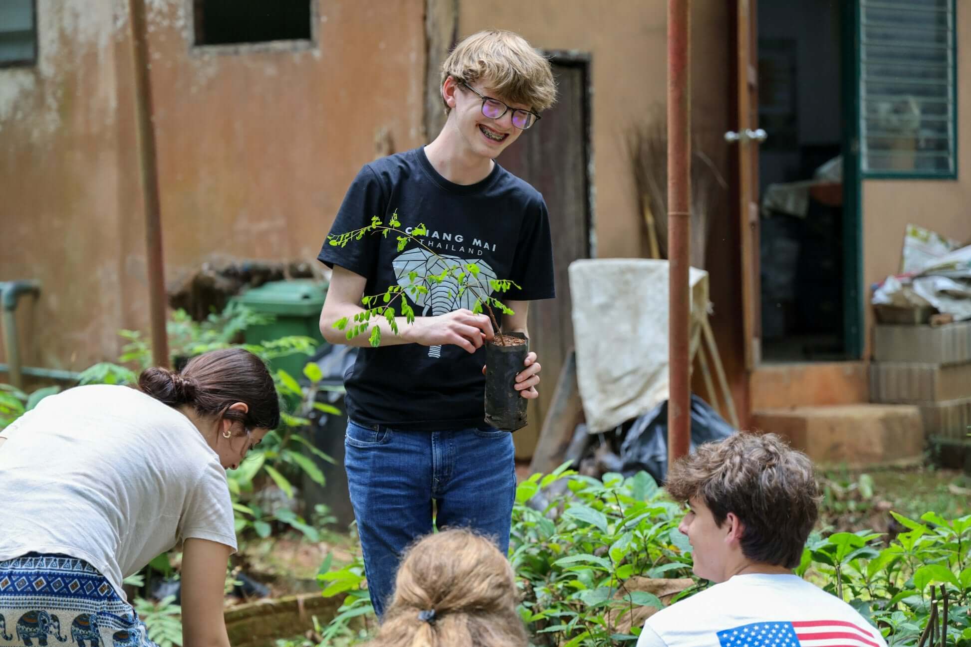 High school students engaging in hands-on activities, planting in a community garden in Thailand.