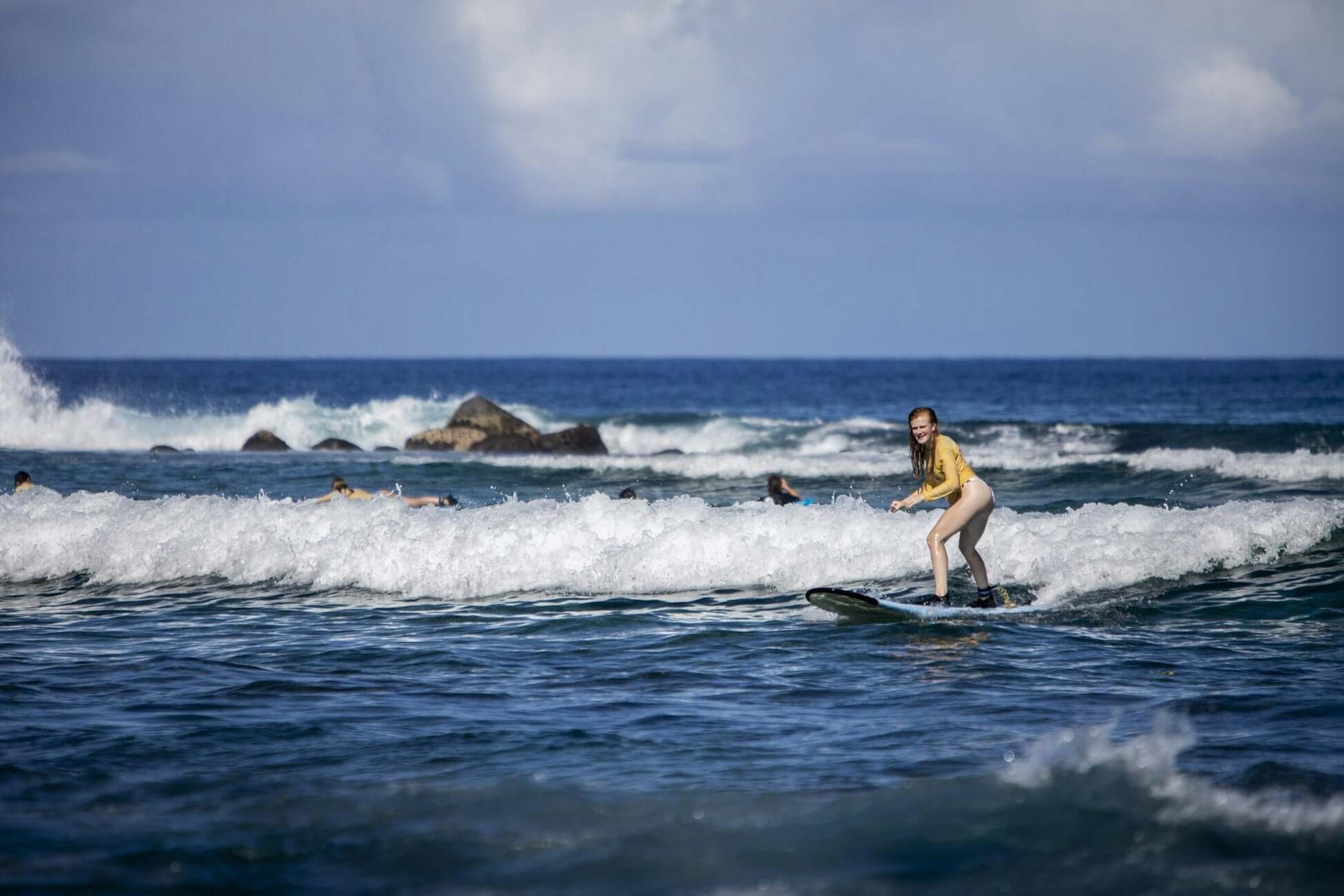 teen surfing in Hawaii, enjoying waves during a summer surf experience by the ocean.