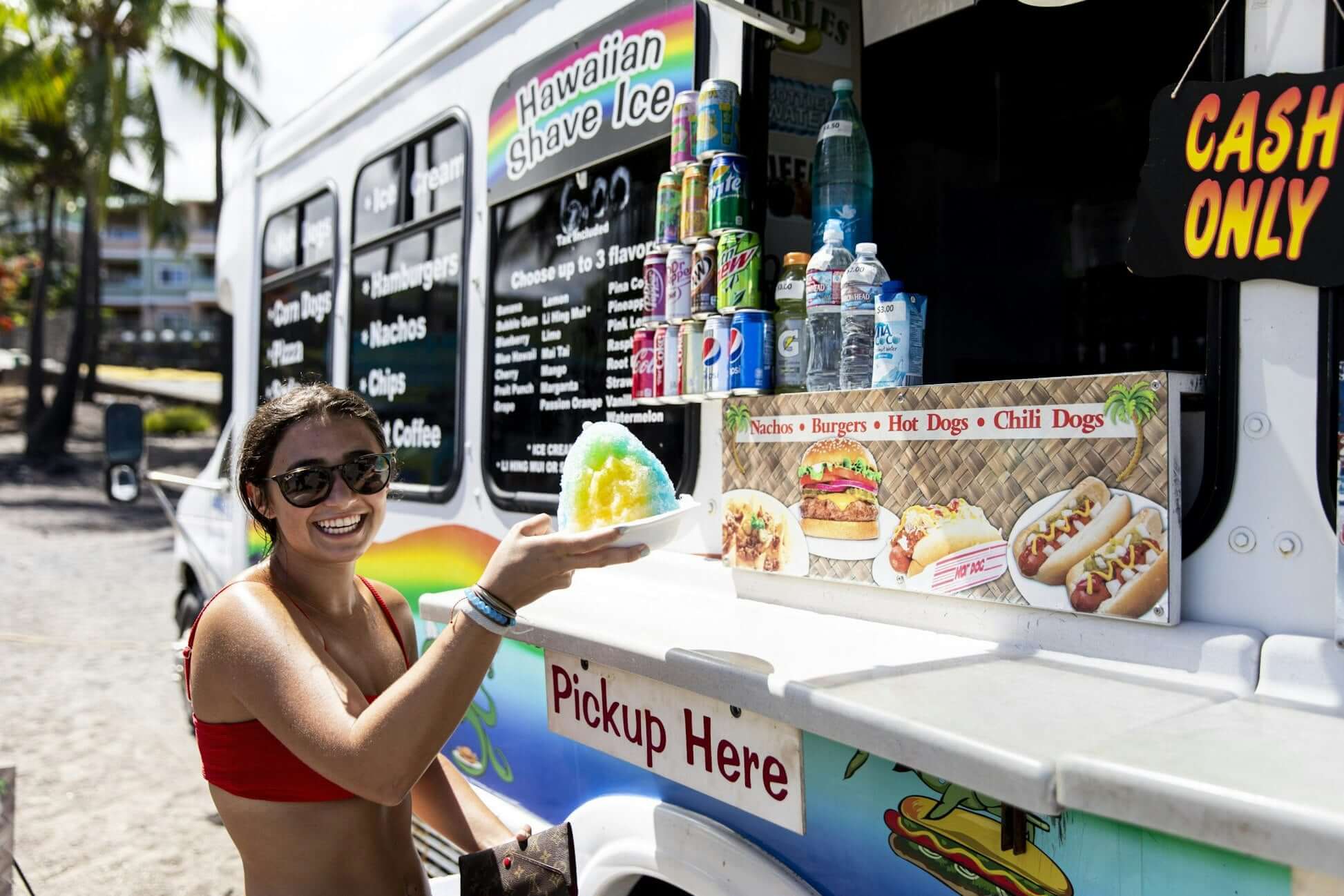 Teen enjoying Hawaiian shave ice from a beachside food truck, highlighting summer treats in Hawaii.