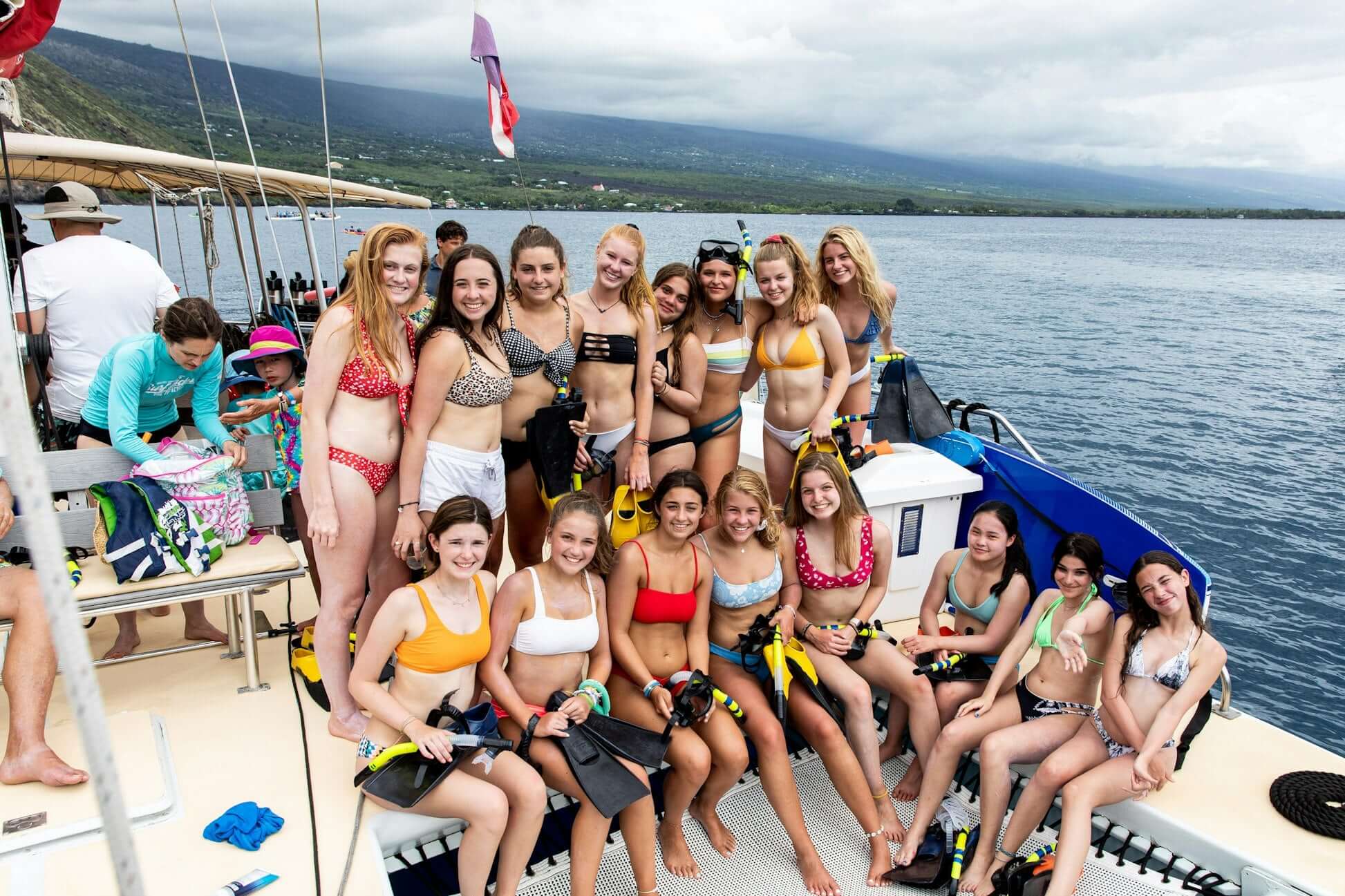 High school summer teens enjoying a snorkeling adventure in Hawaii on a boat, wearing swimwear and smiling happily.