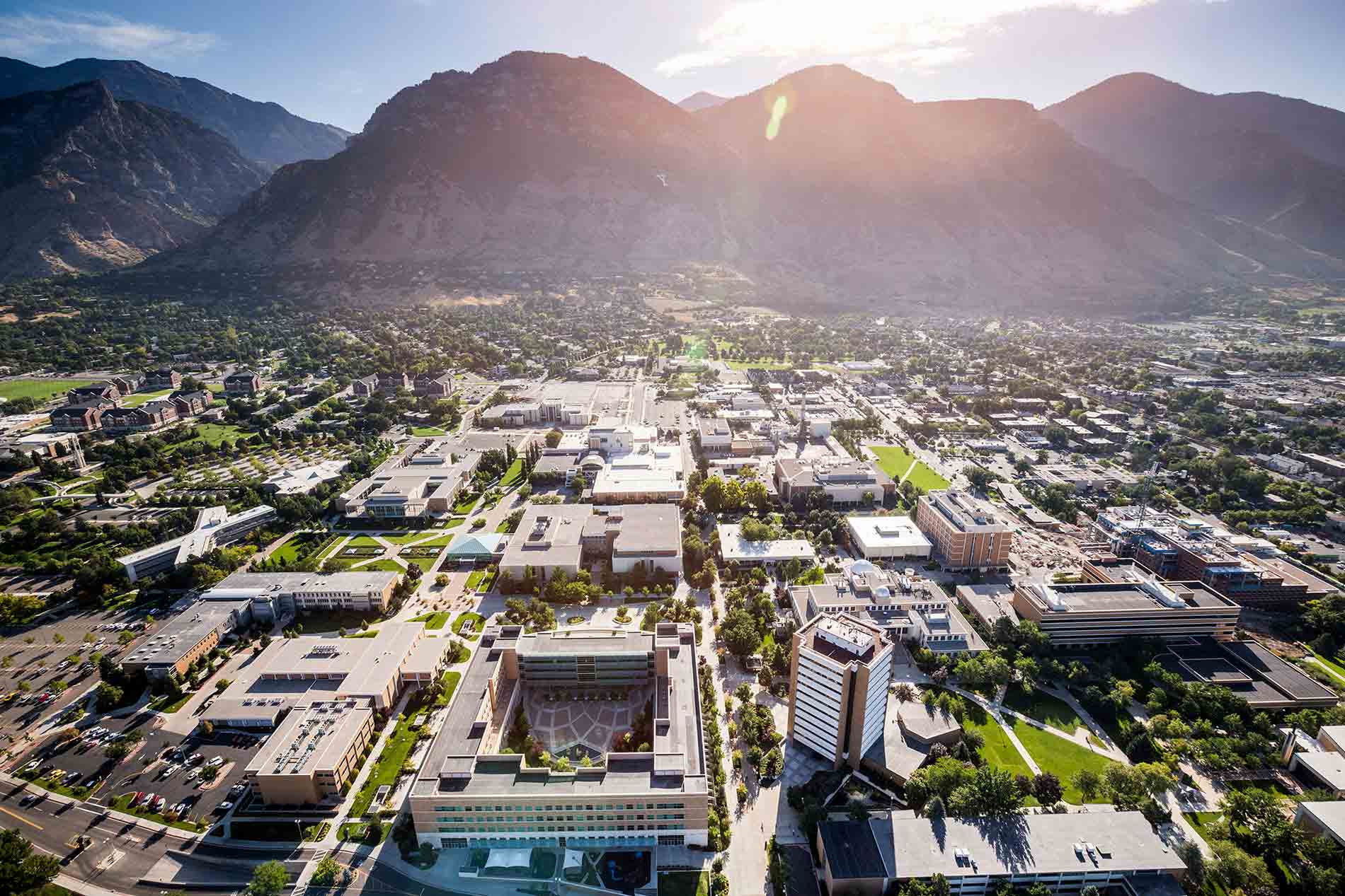 Aerial view of a college campus surrounded by mountains, showcasing green spaces and buildings for summer programs.