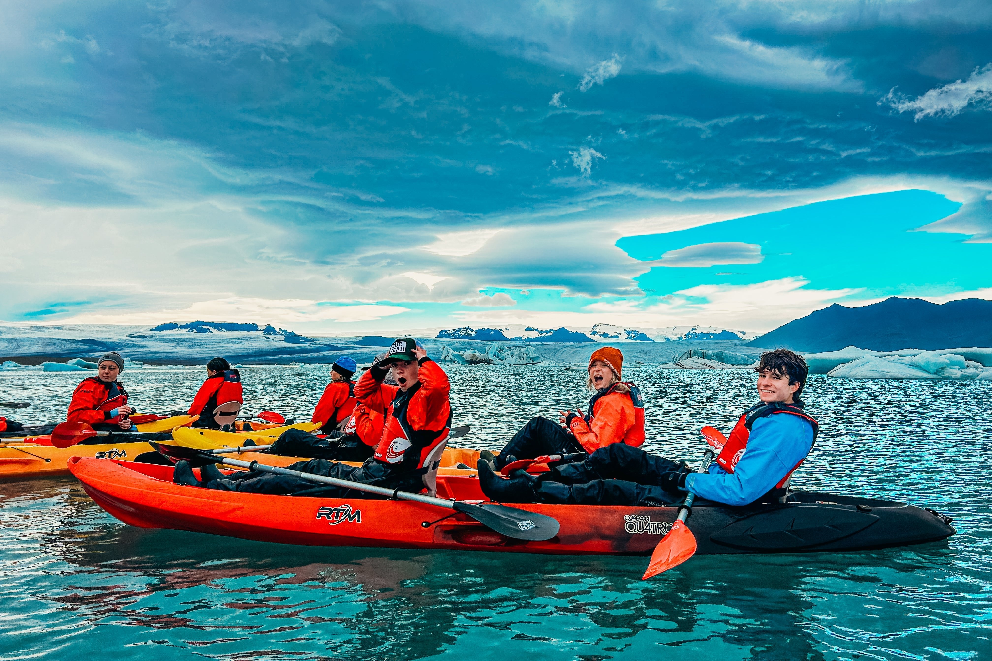 Teen travelers kayaking in a glacial lagoon in Iceland, enjoying summer programs for high school students.