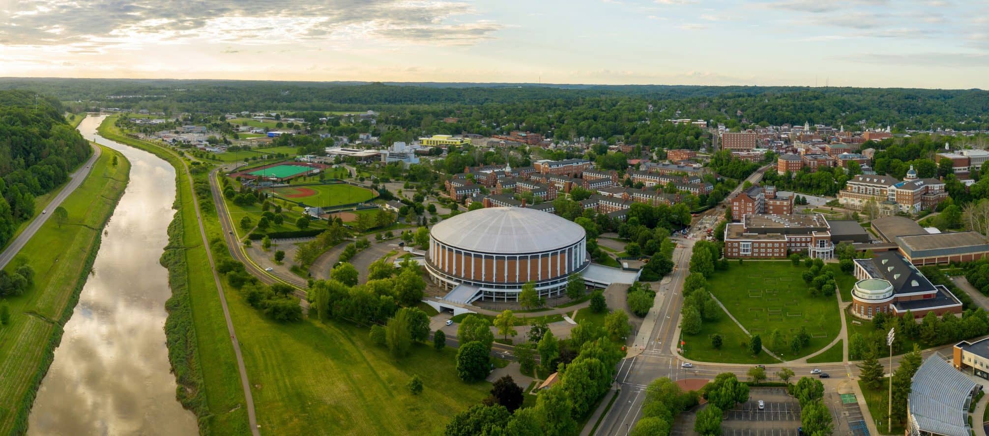 Aerial view of a college campus near a river, showcasing summer activities and facilities for high school and middle school students.