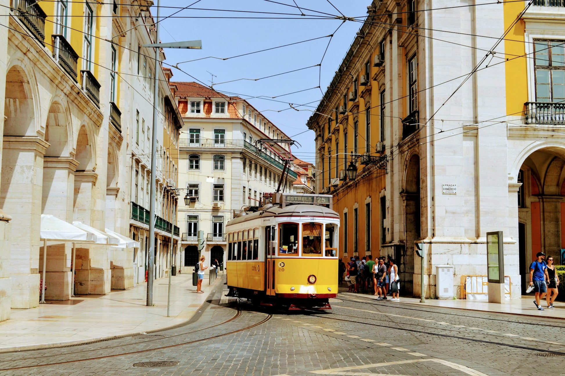 Vintage yellow tram navigating through the charming streets of Lisbon, Portugal, showcasing the city's vibrant architecture.