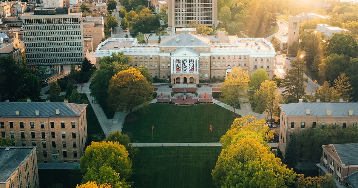 Aerial view of a college campus surrounded by trees, showcasing a central building, ideal for summer programs and high school camps.