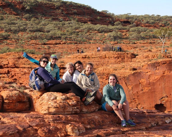 Group of students enjoying summer programs outdoors on rocky terrain in a scenic landscape.