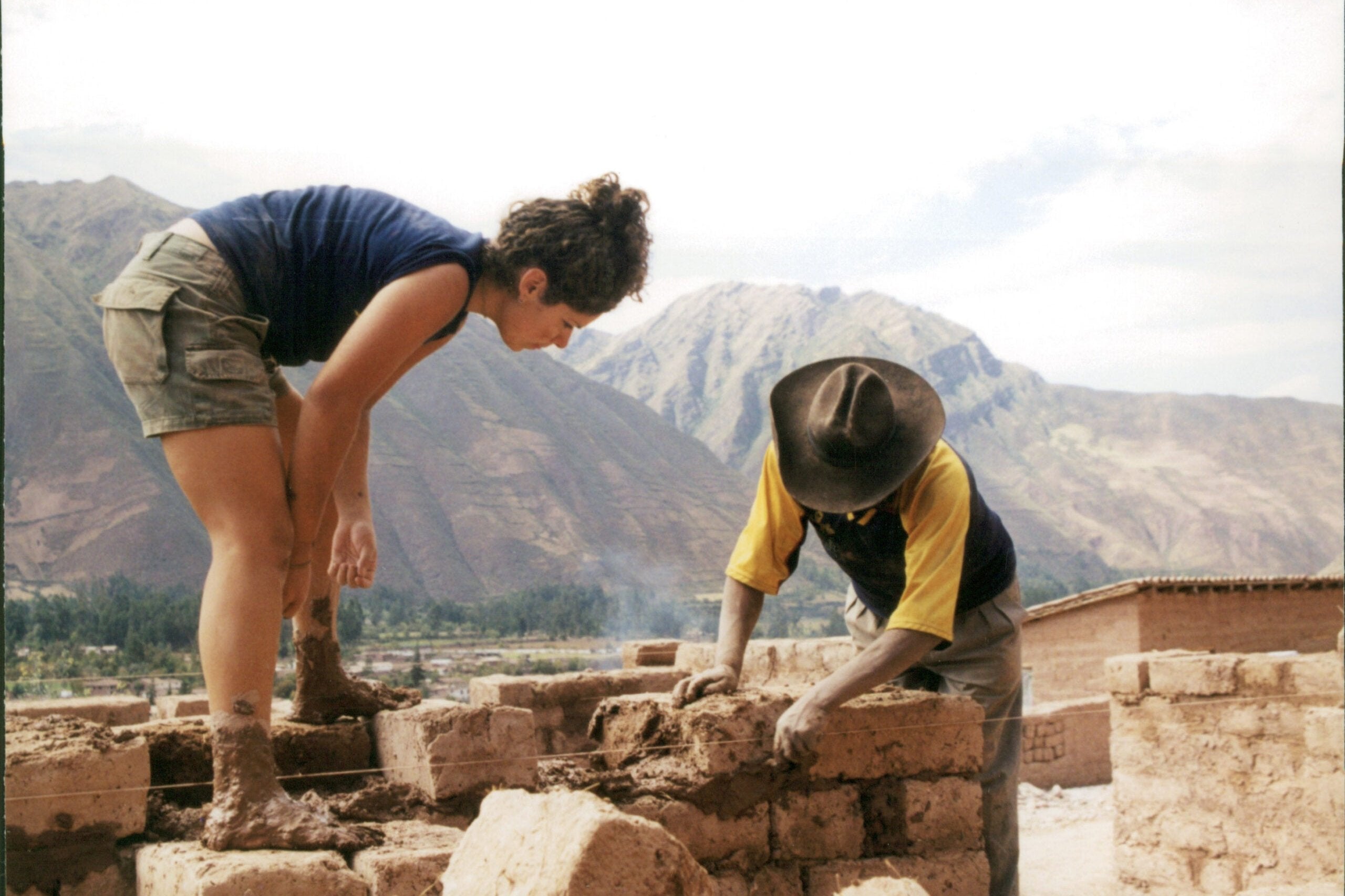 Teens assisting Quechua workers in sustainable building projects in the Andes, enhancing summer travel experiences.