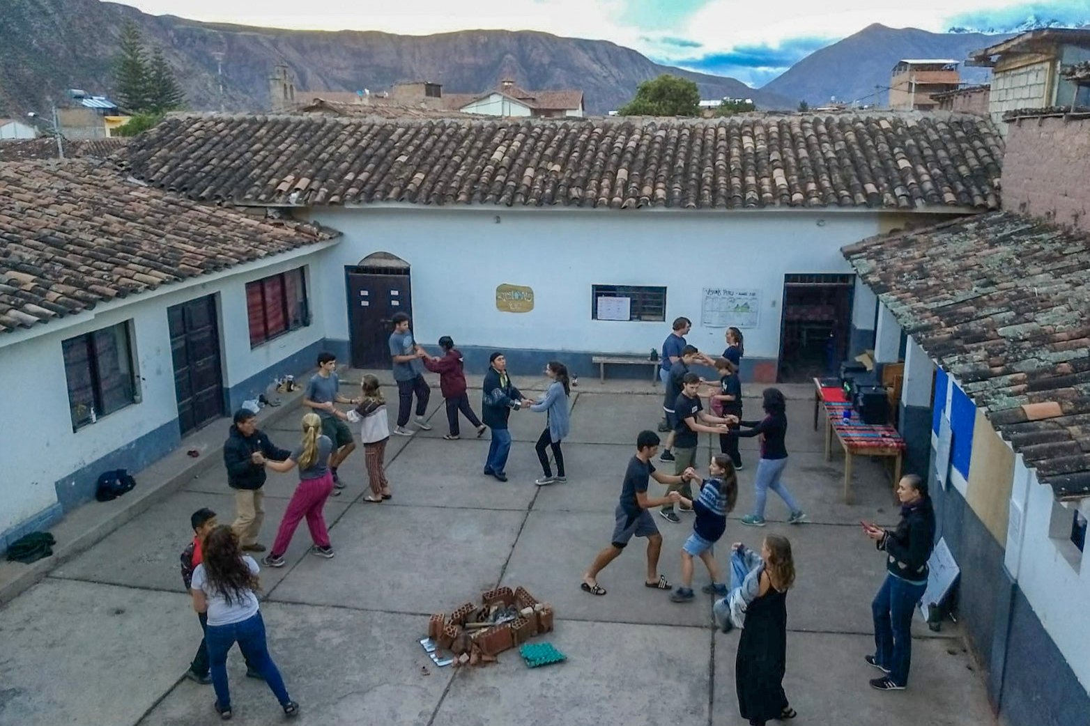 Participants engaging in a traditional dance in a courtyard during summer programs in Peru with the Quechua community.