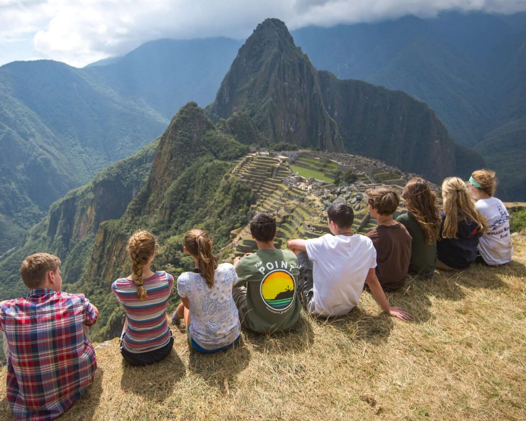 Group of young travelers overlooking Machu Picchu in Peru, enjoying the scenic mountains and cultural heritage.