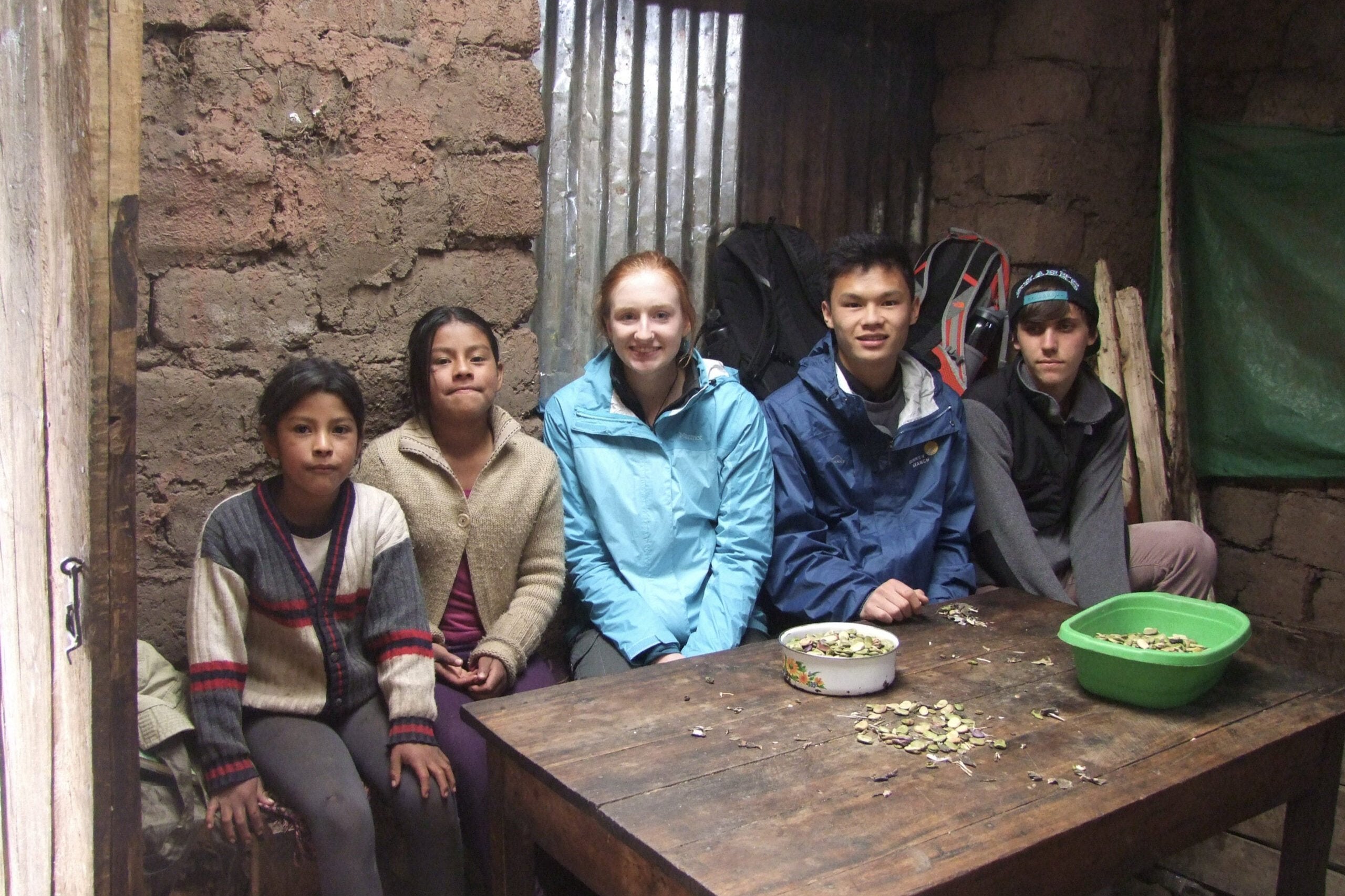Group of high school students with local Quechua children in a rustic home, engaging in cultural exchange in Peru.
