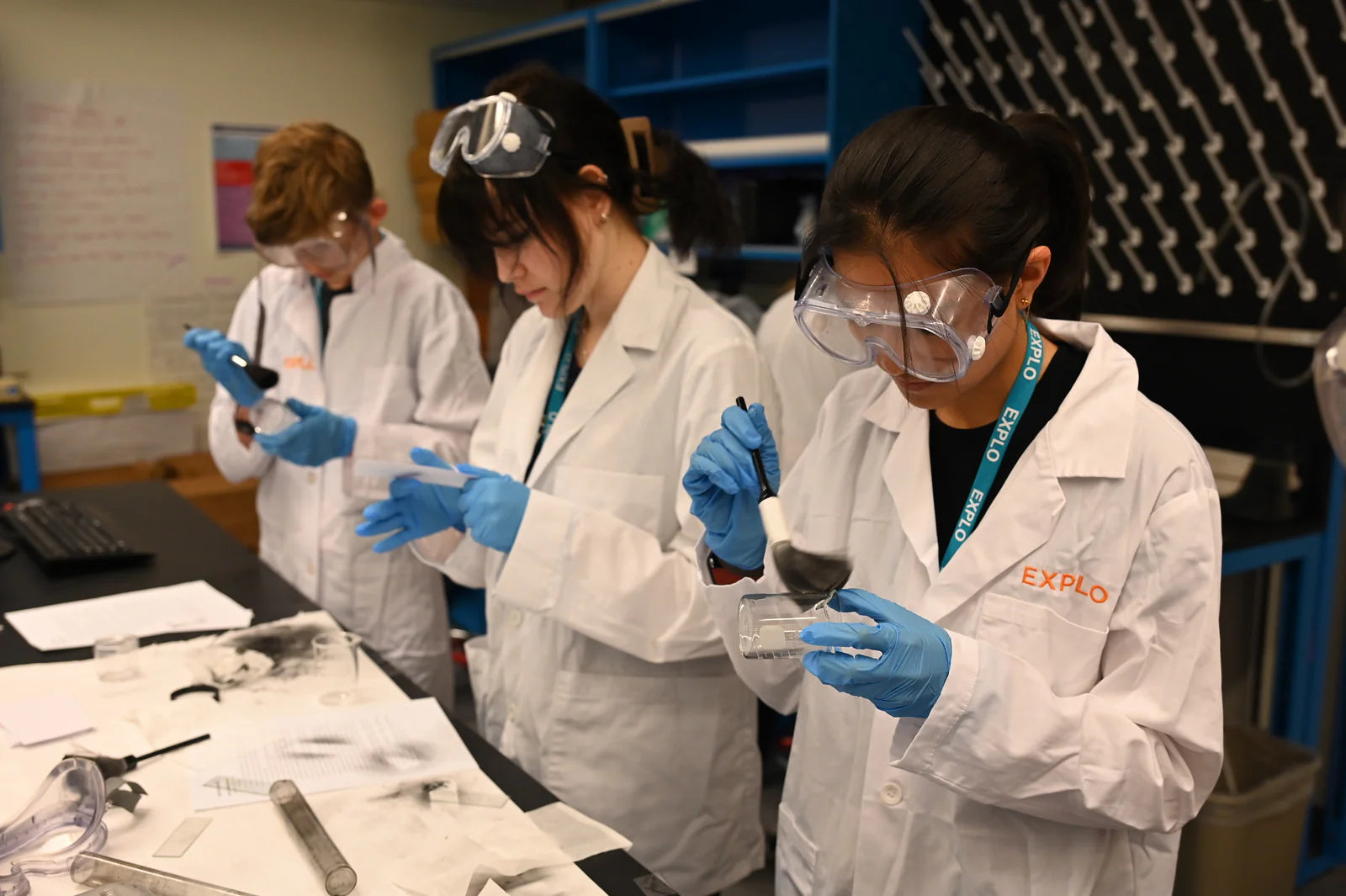 Students engaging in a science experiment at a summer camp, wearing lab coats and safety goggles, focused on their tasks.