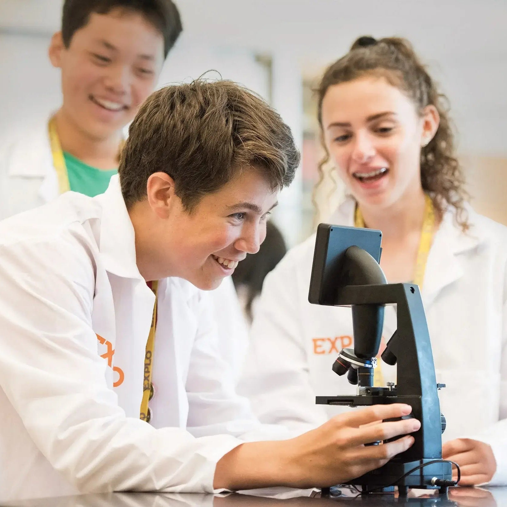 Middle school students engaged in a summer program science workshop, exploring with a microscope at EXPLO.
