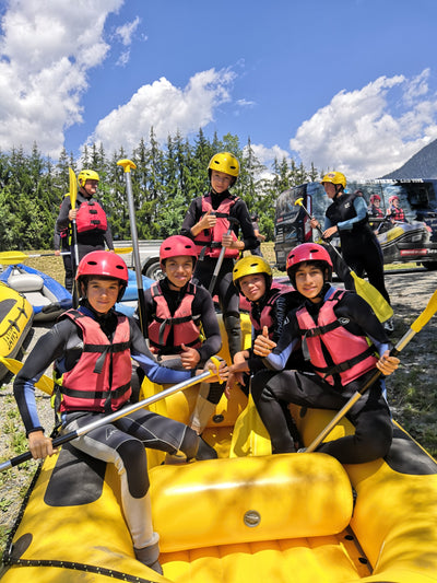 Teens in pink life vests enjoying rafting at a summer camp in the French Alps, ready for adventure and new friendships.