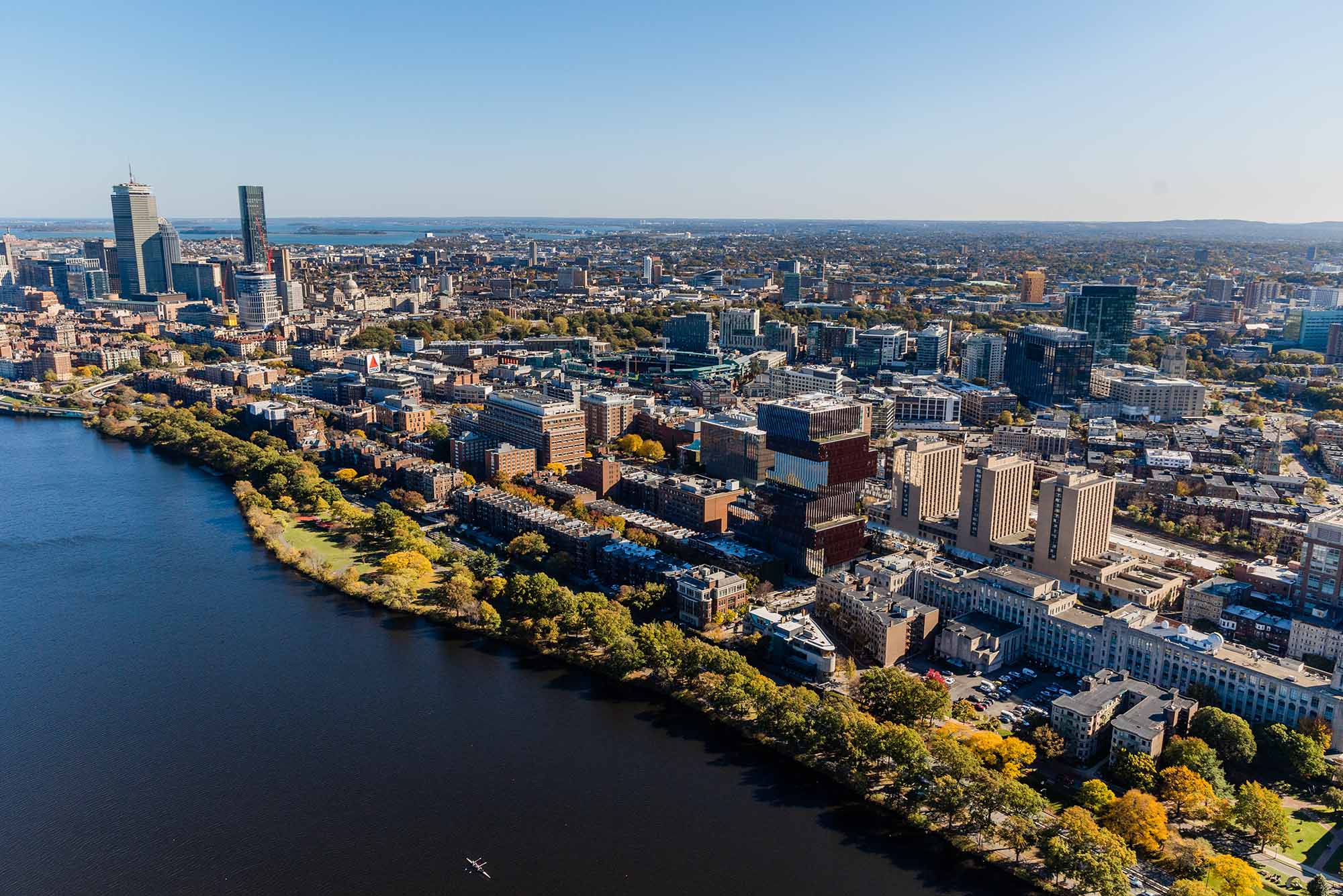Aerial view of a city skyline along the river showing buildings and greenery on a clear day.