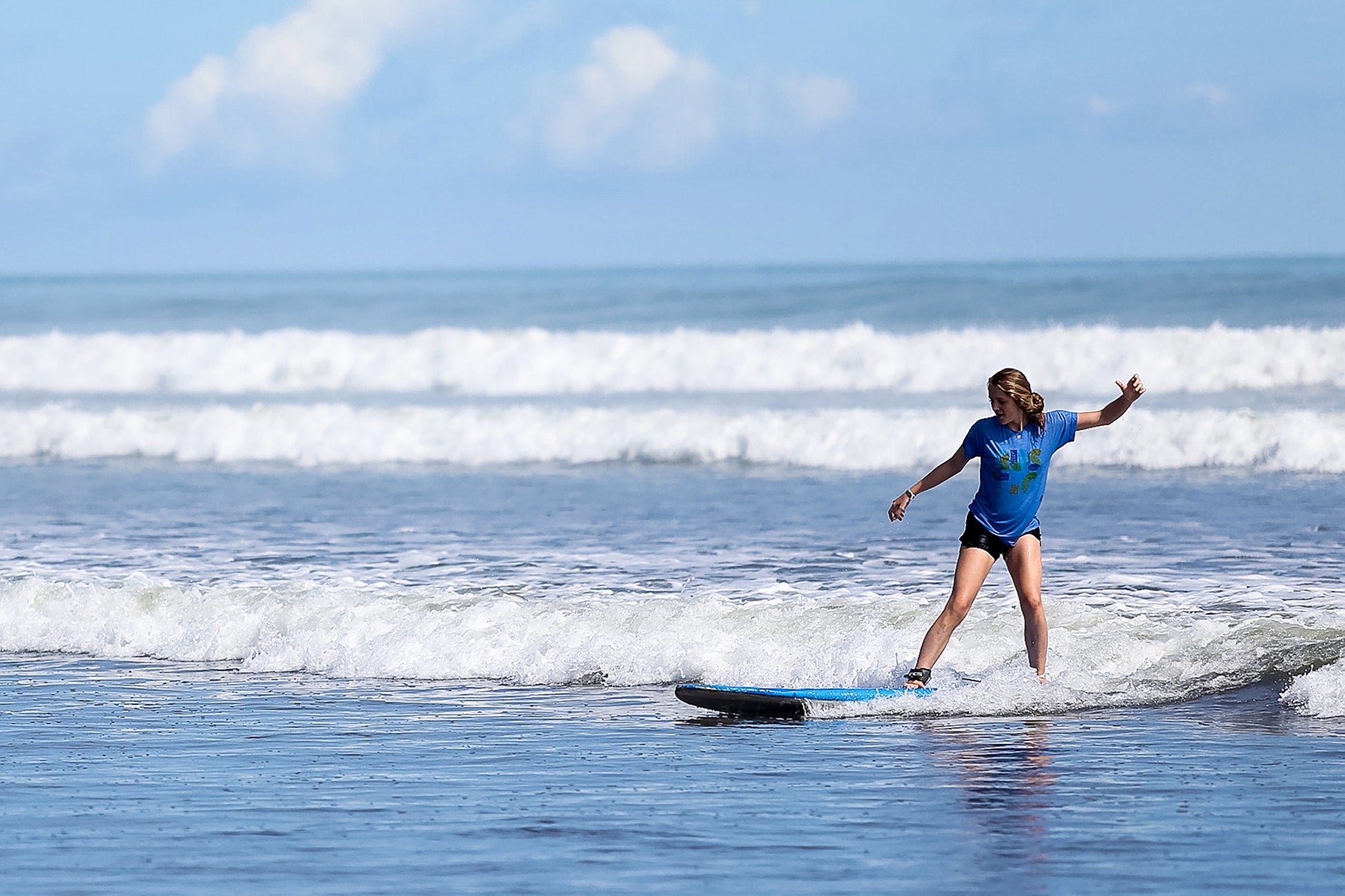 High school student enjoying surf lessons on a sunny beach in Portugal, embracing summer programs and teen travel adventures.