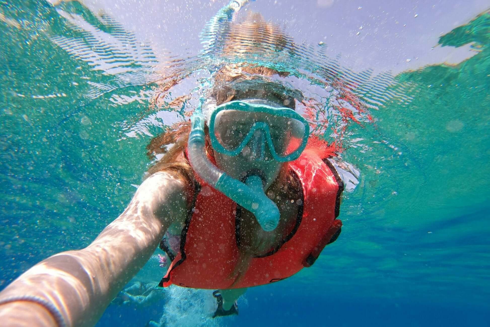Snorkeler in a life jacket underwater, enjoying the vibrant marine life during a summer program in Greece.