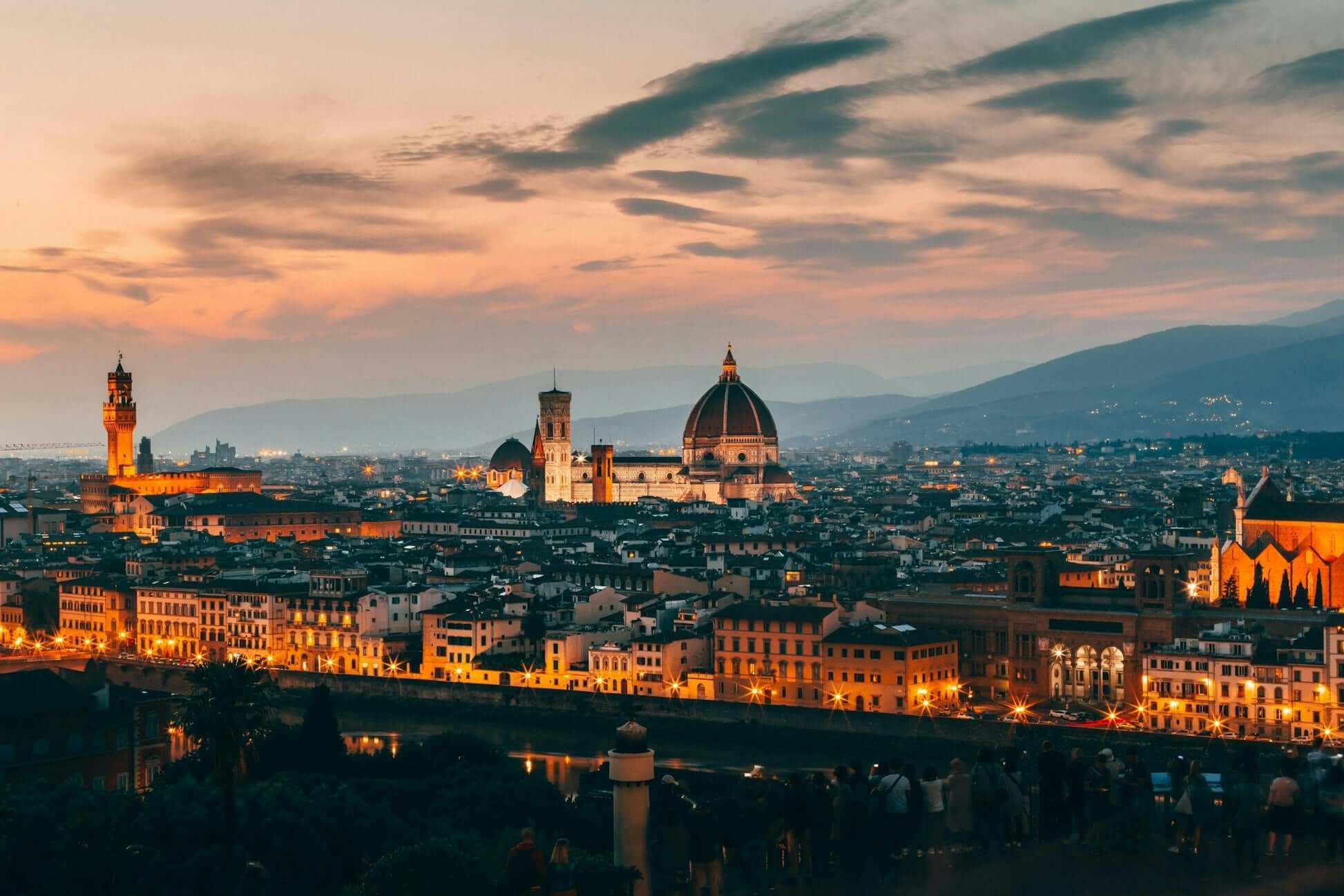 Scenic sunset view of Florence, Italy, showcasing historic buildings and the iconic dome against a vibrant sky.