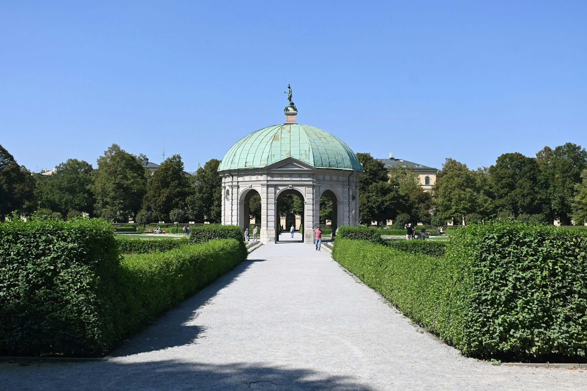 Scenic view of a historic gazebo surrounded by lush greenery in a sunlit park. Perfect for summer strolls and relaxation.