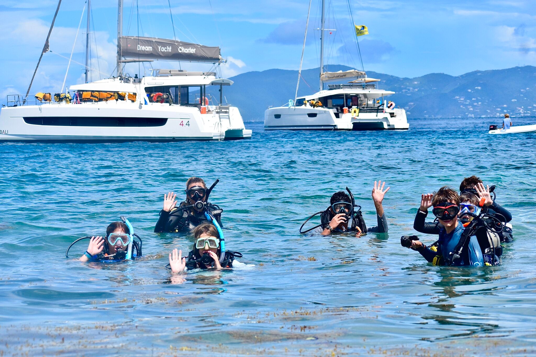 Teen students in scuba gear waving while exploring the Caribbean during summer programs and camps.