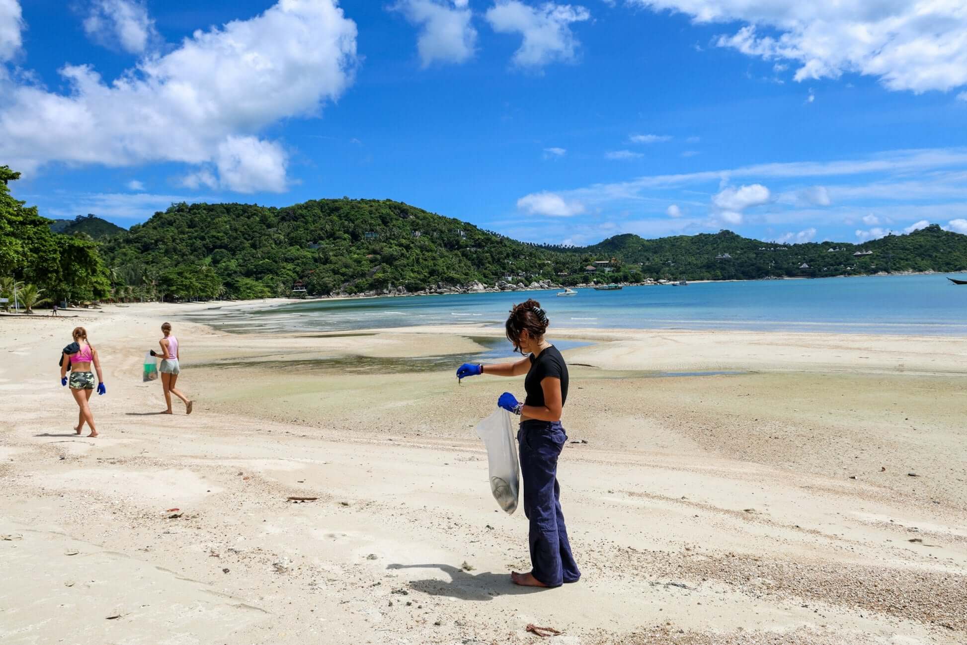 Students participating in marine conservation efforts on a beach in southern Thailand, promoting eco-friendly practices.