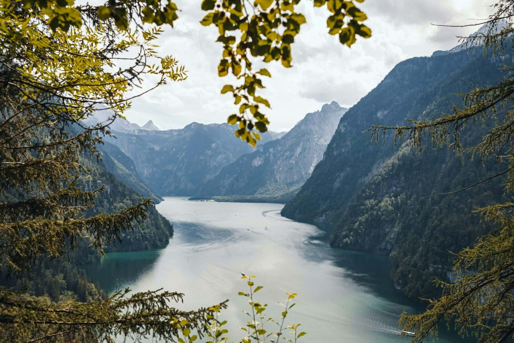 Scenic view of a tranquil lake surrounded by mountains and lush greenery in the Bavarian Alps. Perfect for summer adventures.
