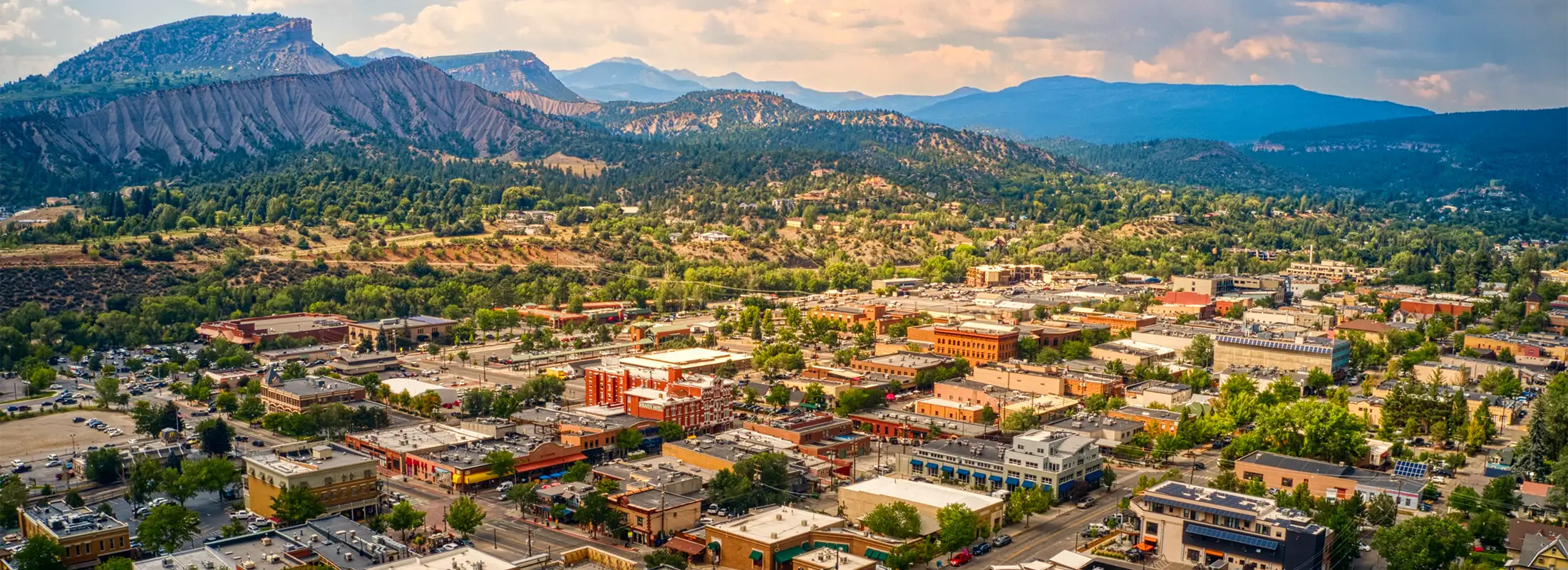 Aerial view of a vibrant town surrounded by mountains, showcasing lush greenery and diverse architecture.