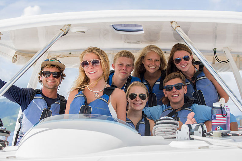 Group of teens in life jackets on a boat, enjoying summer adventures in the Caribbean.