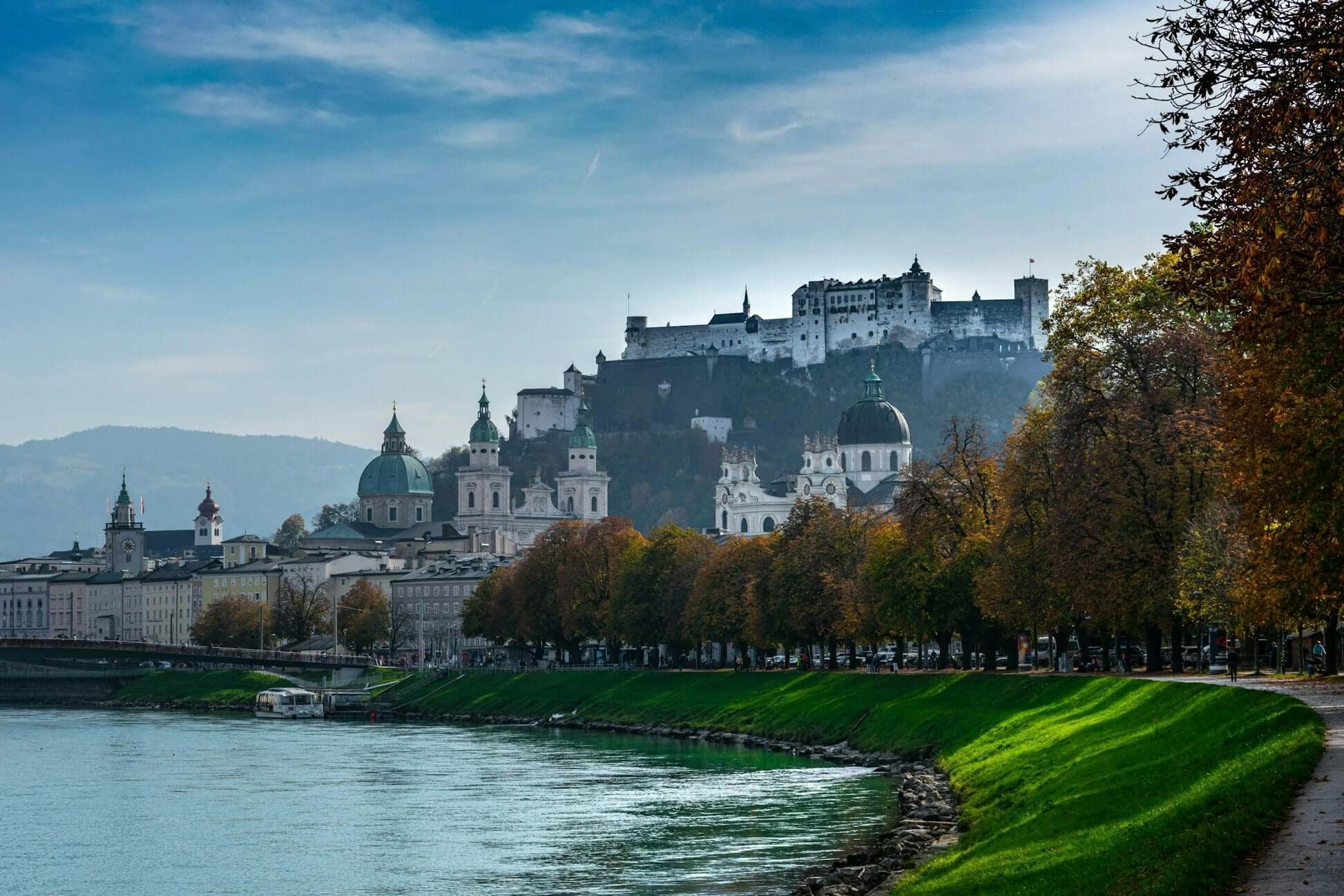 Scenic view of Salzburg with historic architecture and vibrant autumn foliage beside the river. Ideal for summer programs and teen travel.